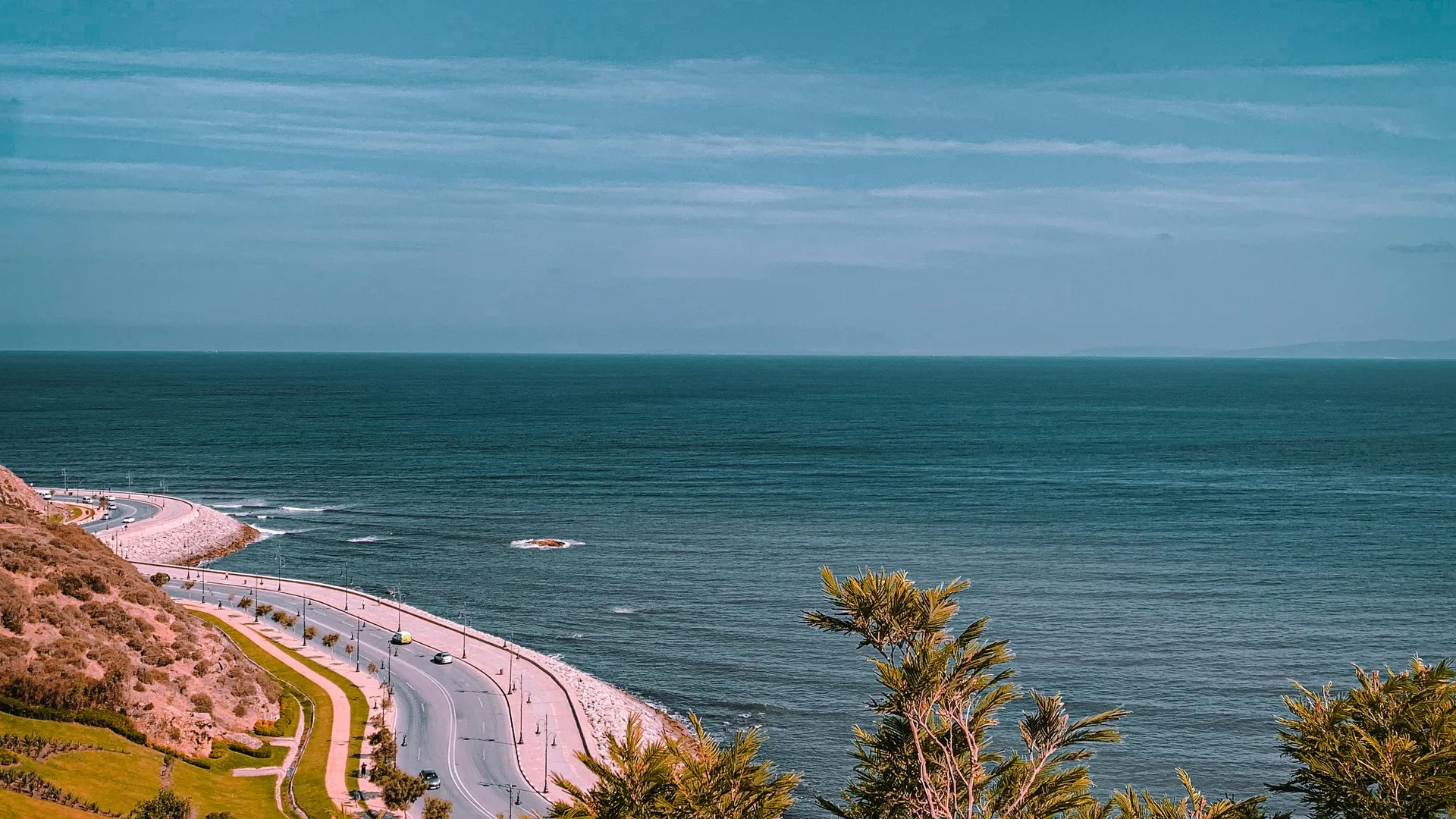 Route côtière sinueuse longeant les falaises atlantiques marocaines — la P8 a ce profil entre Aourir et Taghazout