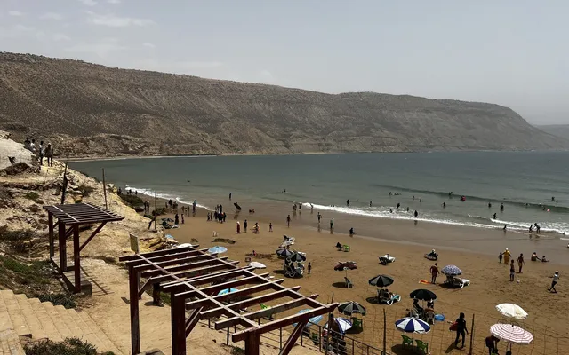Imsouane Bay seen from the cliff road — a long, sheltered cove on the Moroccan Atlantic with a small fishing village at its head