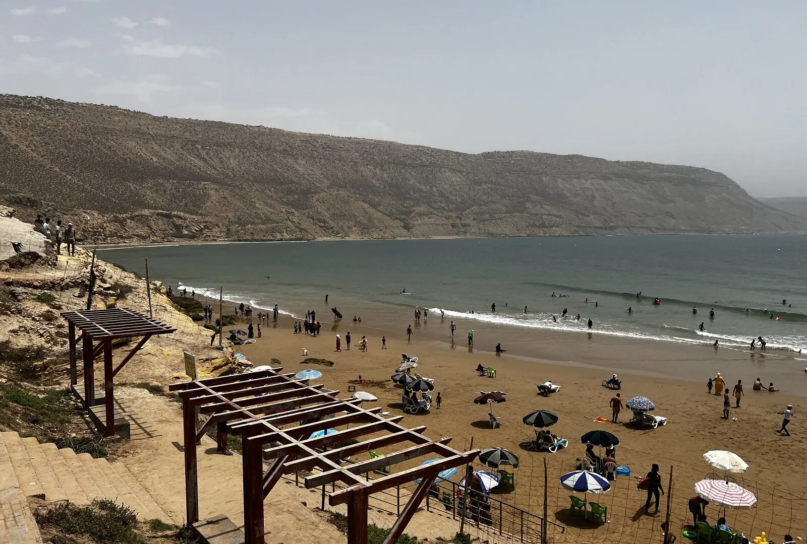Imsouane Bay seen from the cliff road — a long, sheltered cove on the Moroccan Atlantic with a small fishing village at its head