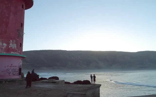 Imsouane Bay at sunrise — surfers lined up on the long right-hand wall of the Cathedral, one of the longest waves in North Africa
