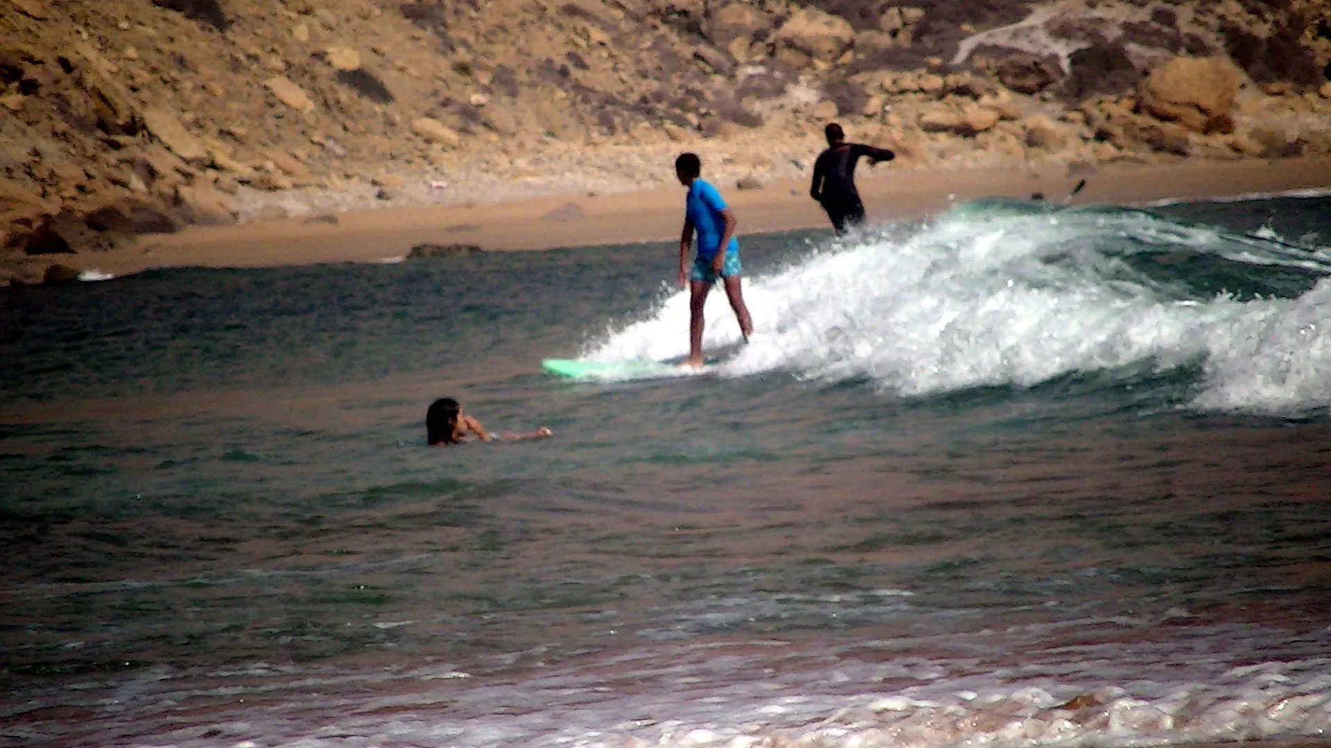 A surfer riding a right-hander at Imsouane — second surfer paddling in the background, the typical rocky bottom of the spot