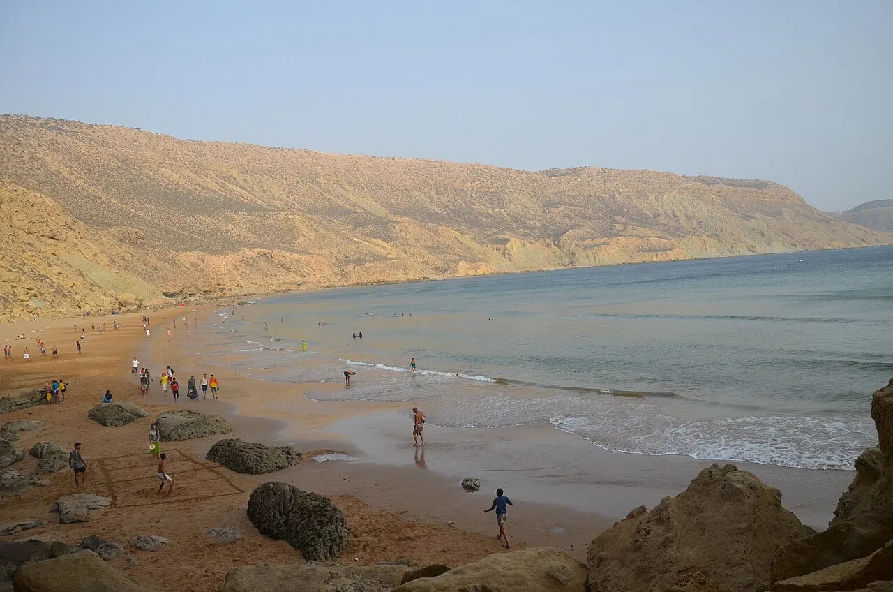 Imsouane's South Beach seen from the rocks — the bay opens north with the hills in the background
