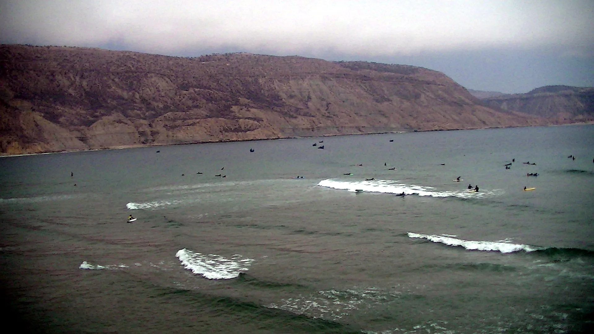 Lineup de surfeurs au peak — densité typique d'un point break marocain aux meilleurs jours de la saison hivernale