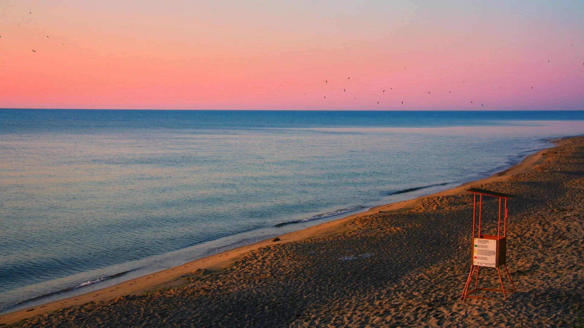 Plage atlantique calme au coucher du soleil — la saison creuse mai-août, avec houles rares et vents du nord constants