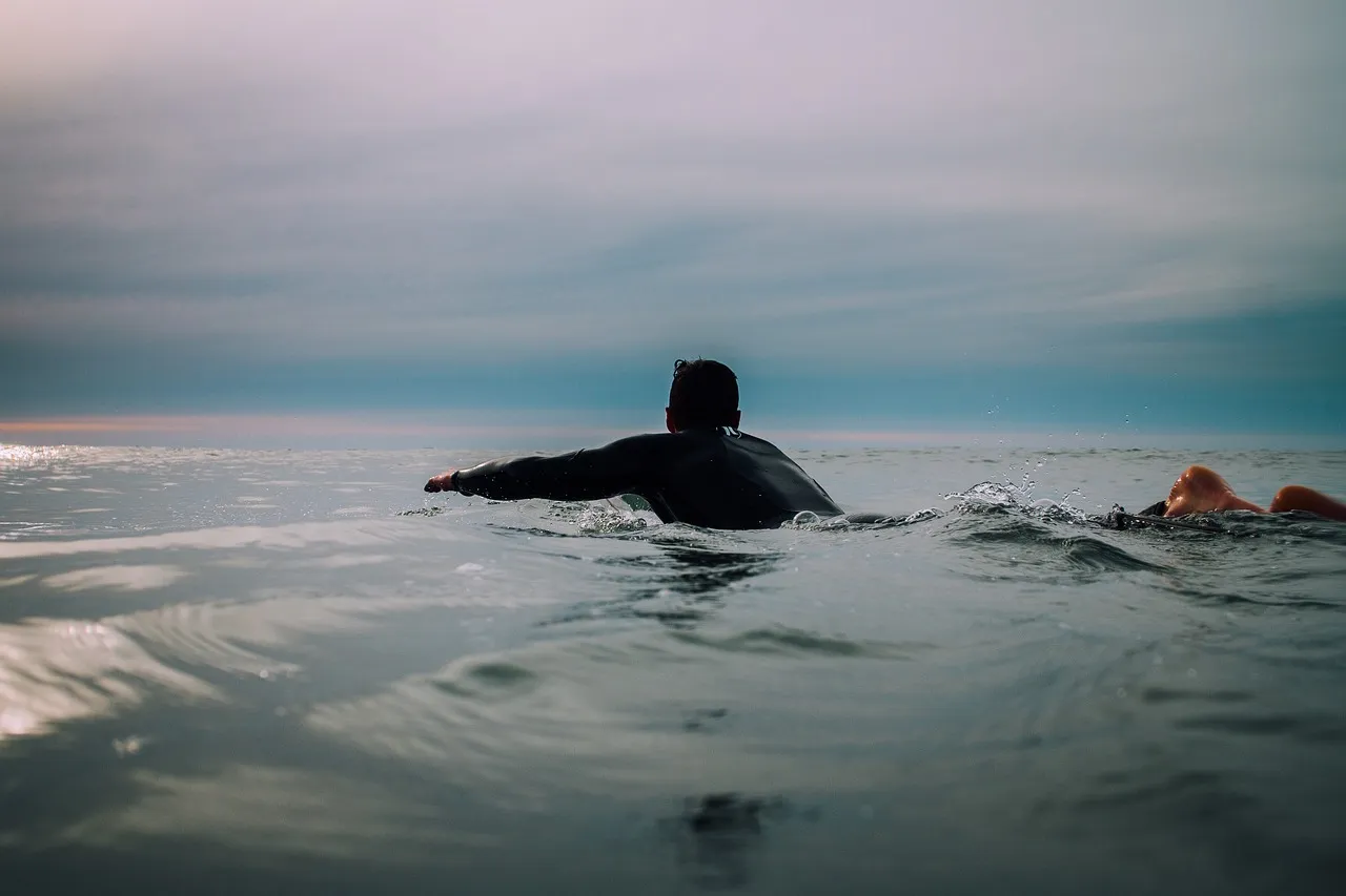 Wetsuited surfer paddling out to the lineup — the target guest profile of the Radisson Blu, in line with its Surf Village positioning