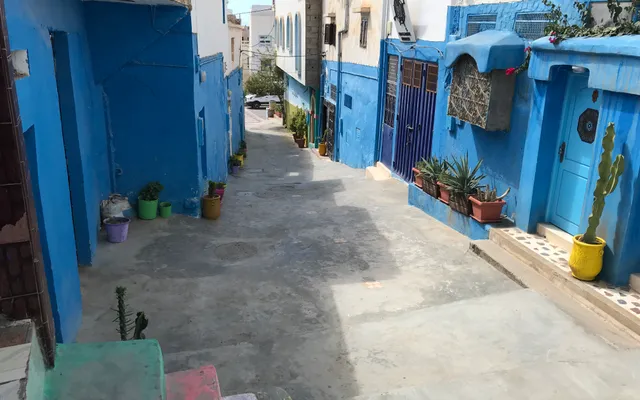 Traditional Taghazout lane lined with blue-and-white houses — the local reference behind the contemporary architecture of the Fairmont Taghazout Bay